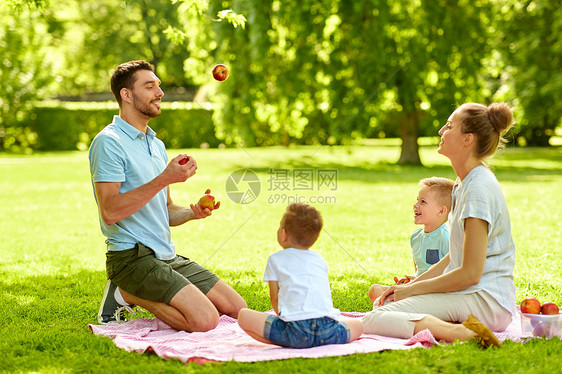 家庭,休闲人的快乐的母亲,父亲杂耍苹果两个小儿子夏季公园野餐快乐的家庭夏天的公园野餐图片