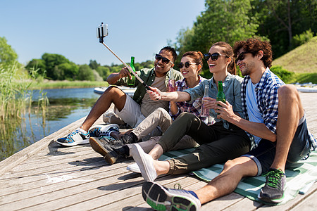 休闲,野餐技术朋友与饮料拍照自拍杆湖墩夏季公园饮料的朋友湖码头自拍图片