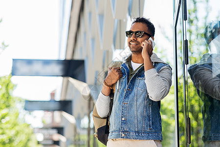 旅行,旅游生活方式的微笑的印度男子与背包呼叫智能手机城市街道带背包的男人城市打电话给智能手机图片