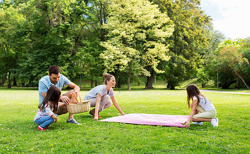一家人在公园的草地上铺设野餐毯图片