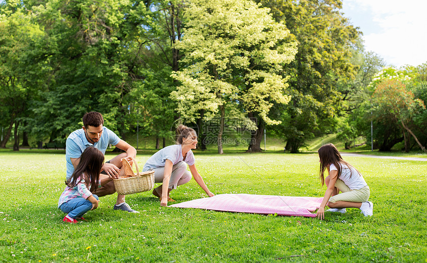 一家人在公园的草地上铺设野餐毯图片