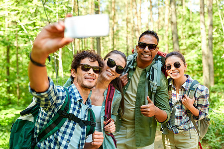 旅行,旅游,徒步旅行人的群朋友带着背包森林里用智能手机自拍朋友们带着背包徒步旅行自拍图片
