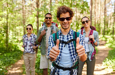 旅行,旅游,徒步旅行人们的群朋友带着背包男人森林里竖大拇指的手势背包的朋友森林里竖大拇指图片