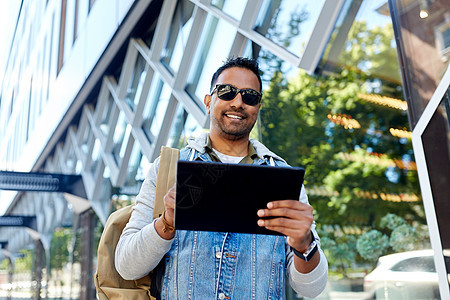 旅行,旅游生活方式的微笑的印度男子与平板电脑背包城市街道城市街道上平板电脑背包的男人图片