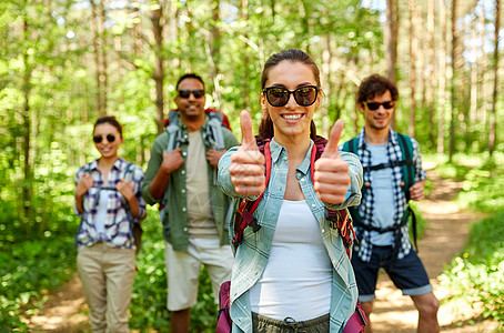 旅行,旅游,徒步旅行人们的群朋友带着背包女人森林里竖大拇指的手势背包的朋友森林里竖大拇指图片