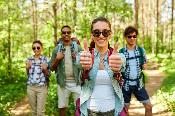 旅行,旅游,徒步旅行人们的群朋友带着背包女人森林里竖大拇指的手势背包的朋友森林里竖大拇指图片