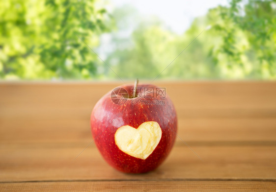 水果,食物健康成熟的苹果,雕刻的心形木制桌子上绿色的自然木桌上雕刻心形的红苹果图片