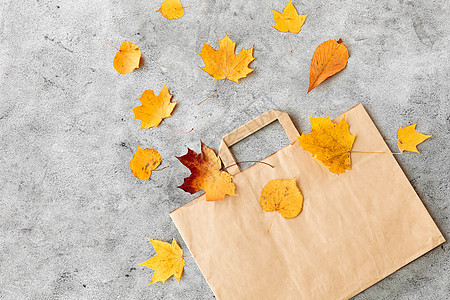 购物旺季销售秋天的树叶纸袋灰色的石头背景灰色石头上的秋叶纸袋图片