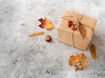 礼物包装纸自然季节礼品盒包装成邮政包装纸,秋叶,栗子,橡子玫瑰浆果灰色的石头背景礼品盒,橡子玫瑰背景