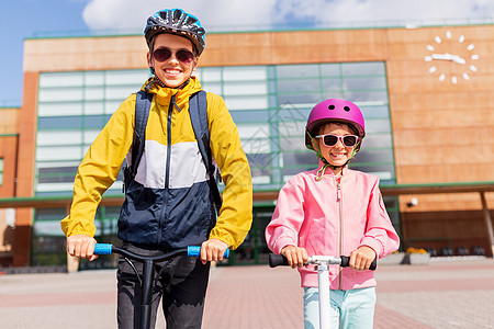 教育,童人的快乐的学校孩子戴着头盔,背包骑着滑板车户外快乐的学校孩子戴着头盔骑滑板车图片