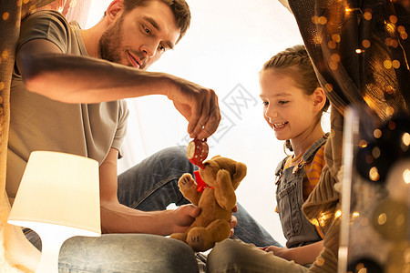 家庭,潮格人的快乐的父亲小女儿玩泰迪熊玩具茶壶孩子们的帐篷晚上家快乐的家庭孩子们的帐篷里玩玩具图片
