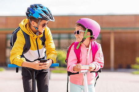 教育,童技术快乐的学校孩子戴着头盔,户外玩智能手机滑板车智能手机滑板车的学童图片