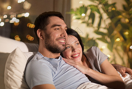 人,家庭休闲的快乐的夫妇晚上家床上看电视快乐的夫妇晚上家床上看电视背景图片