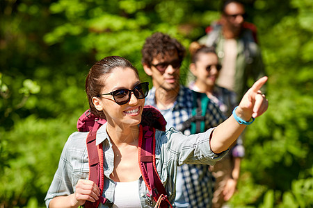 旅行,旅游,徒步旅行人们的女人向群朋友展示些东西,带着背包森林里散步群带背包的朋友森林里徒步旅行图片