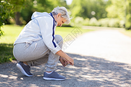 健身,运动健康的生活方式老年女子夏季公园系鞋带夏季公园系运动鞋鞋带的老年女子图片