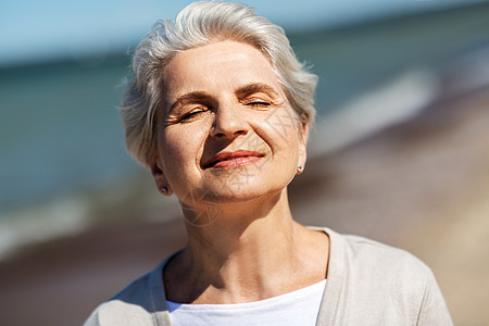 人与休闲的快乐的老妇女海滩上享受阳光的肖像海滩上享受阳光的高级女人的肖像图片