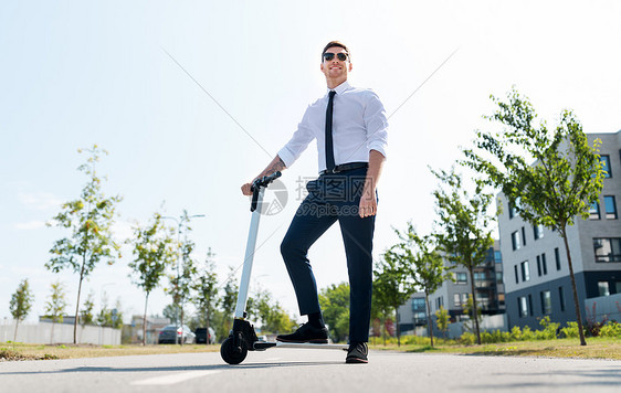 商业人轻商人骑电动滑板车户外轻的商人户外骑电动滑板车图片