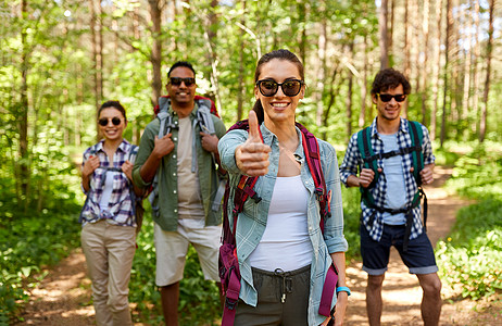 旅行,旅游,徒步旅行人们的群朋友带着背包女人森林里竖大拇指的手势背包的朋友森林里竖大拇指图片