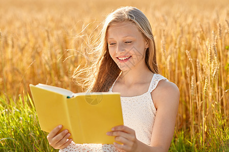 乡村,文学休闲微笑的轻女孩穿着白色连衣裙阅读书谷谷田夏天微笑的轻女孩读谷物领域的书图片