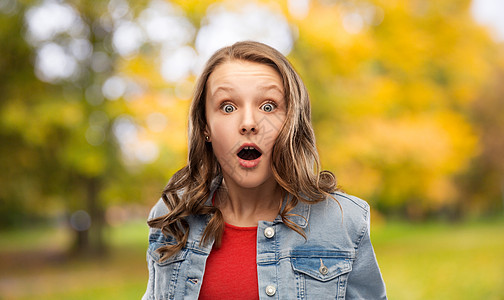 情感,表达人的惊讶震惊的十几岁的女孩张开嘴牛仔夹克秋季公园背景秋天公园里惊讶震惊的十几岁女孩图片