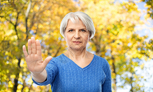 穿着蓝色毛衣的老年女性表示出禁止的手势图片