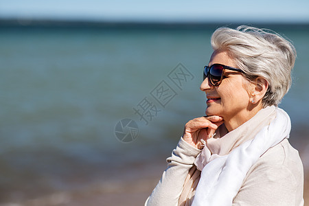 海滩上戴太阳镜的高级女人的肖像图片