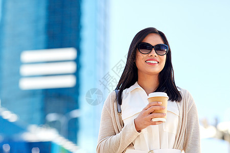 生活方式人们的快乐微笑的轻亚洲妇女戴着太阳镜,城市街道上着外卖咖啡杯微笑的女人带着外卖咖啡杯城市图片