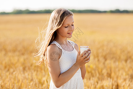 自然,健康的饮食机的微笑的轻女孩着杯牛奶谷物田夏天谷物地里喝杯牛奶的女孩图片