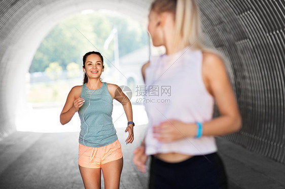 健身,运动健康的生活方式微笑的轻妇女女朋友与耳机运行户外耳机运行的女女朋友图片