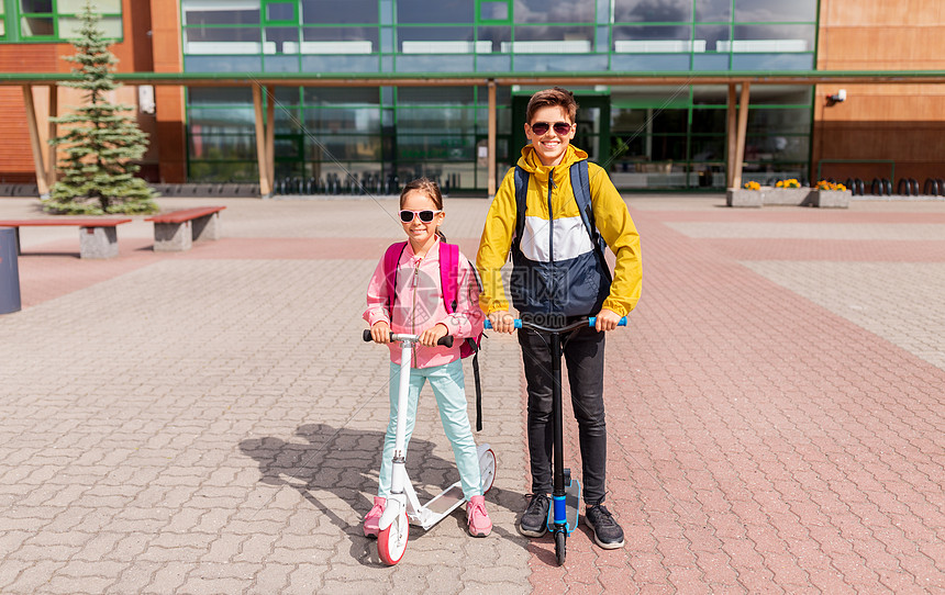 教育,童人的快乐的学校孩子与背包骑滑板车户外带背包的学童骑滑板车图片