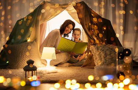 晚上母亲与小女儿在帐篷里看书背景图片