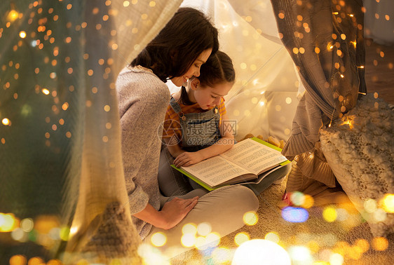 母亲带着孩子在帐篷里读书图片
