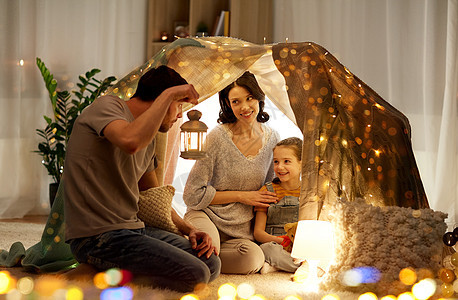 家庭,潮格人的快乐的母亲,父亲带着灯笼,小女儿晚上家里的孩子帐篷里玩快乐的家庭晚上家孩子们的帐篷里玩耍图片