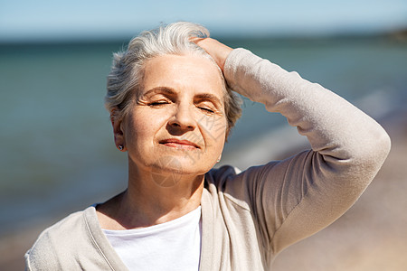老人头菌人与休闲的快乐的老妇女海滩上享受阳光的肖像海滩上享受阳光的高级女人的肖像背景