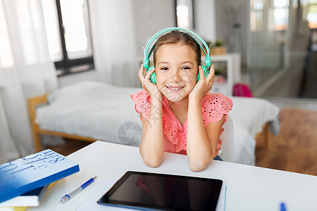 儿童,教育技术快乐的学生女孩耳机与平板电脑家里的办公桌女孩戴着耳机,家里平板电脑图片