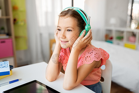 儿童,教育技术快乐的学生女孩耳机与平板电脑家里的办公桌女孩戴着耳机,家里平板电脑图片