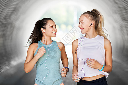 健身,运动健康的生活方式微笑的轻妇女女朋友与耳机运行户外耳机运行的女女朋友图片