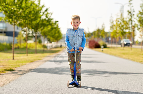 童,休闲趣的快乐的小男孩骑滑板车城市快乐的小男孩城市里骑滑板车图片