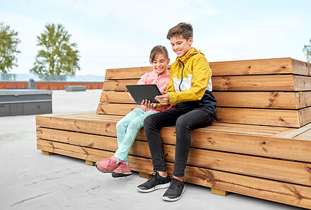 童,技术人的快乐的孩子兄弟姐妹与平板电脑坐木制的街道长凳上户外儿童平板电脑坐长凳上图片