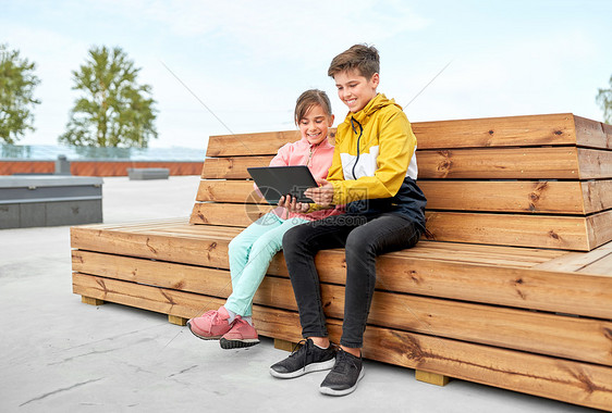 童,技术人的快乐的孩子兄弟姐妹与平板电脑坐木制的街道长凳上户外儿童平板电脑坐长凳上图片
