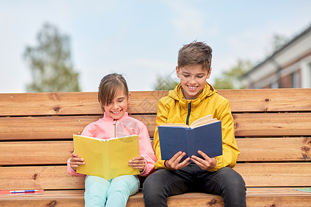 教育,童人的快乐的学校孩子兄妹阅读书籍,坐木制的街道长凳户外学校的孩子们坐长凳上看书图片