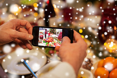 食物技术假日雪上的诞晚餐上,用智能手机拍摄烤火鸡诞节晚餐时双手拍照食物图片