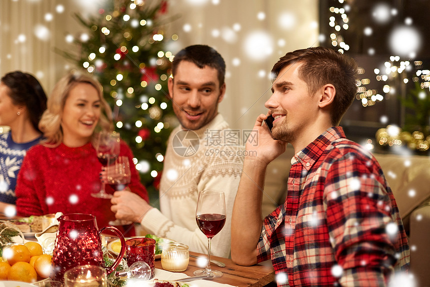 假期,沟通庆祝快乐的轻人打电话给智能手机,并雪地上朋友吃诞晚餐男人诞节晚餐时打电话给智能手机图片