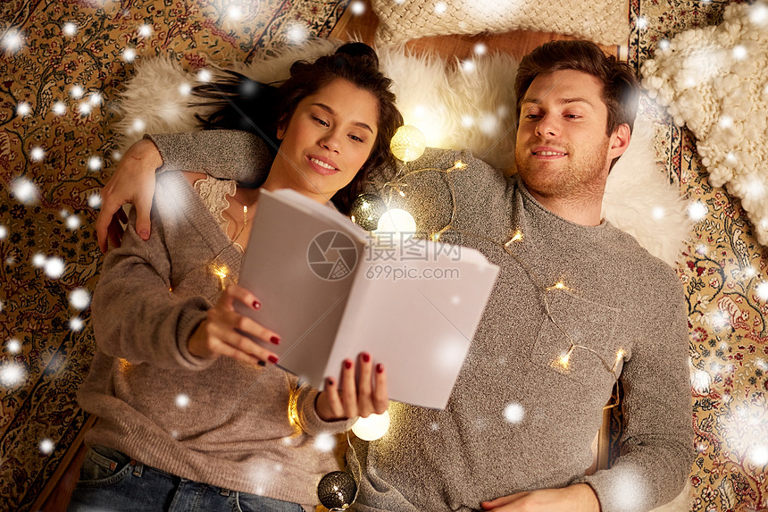 诞节,潮格人们的幸福的夫妇阅读书躺地板上的雪快乐的夫妇家看书图片