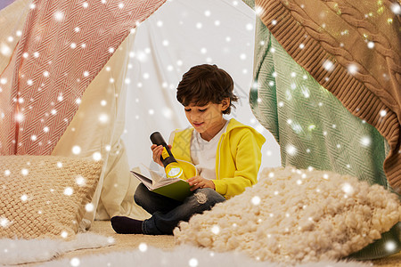 童,诞节人们的快乐的男孩阅读书与火炬灯孩子帐篷帐篷家里的雪快乐的男孩家孩子们的帐篷里看书图片