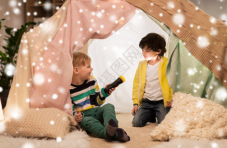 童,诞节友谊的快乐的男孩与火炬灯孩子的帐篷帐篷家里的雪上玩快乐的男孩孩子们的帐篷里放着手电筒图片