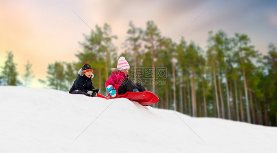 童,雪橇季节的快乐的孩子们冬天滑下雪山的雪橇森林背景下快乐的孩子们冬天乘雪橇下山图片