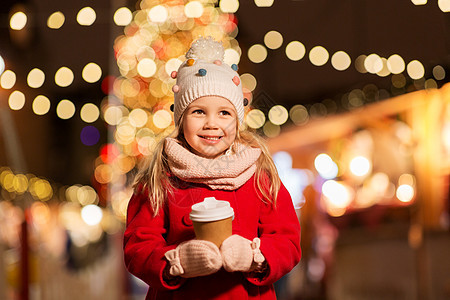 假期,童人的快乐的小女孩诞市场冬天的晚上喝茶诞市场上喝杯茶的快乐女孩图片