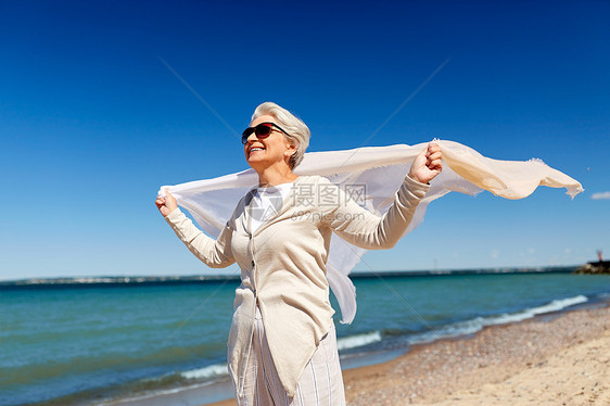 人休闲幸福的老妇女戴着太阳镜,爱沙尼亚海滩上挥动围巾爱沙尼亚海滩上戴着挥动围巾的高级女人图片