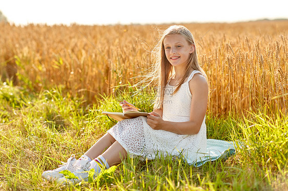 乡村,文学休闲的微笑的轻女孩穿着白色的衣服写日记谷物田夏天微笑的女孩谷物地里写日记图片